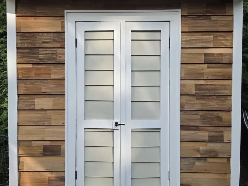 Backyard shed with painted trim and wood plank siding