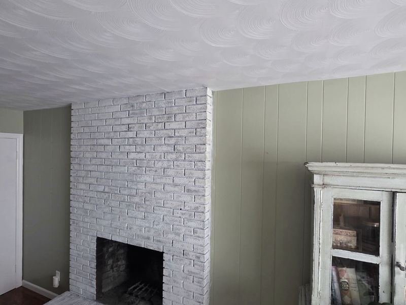 Whitewashed brick fireplace and painted paneling